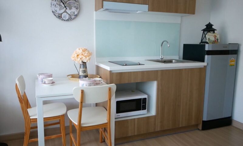 prikaz male kuhinje u garsonjeri sa malim stolčicem, par kuhinjskih elemenata, mikrotalasnom, sudopera i šporet