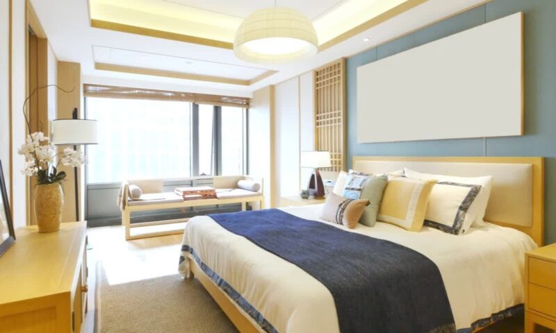 prikaz dobro osvetljene spavaće sobe sa velikim bračnim krevetom na kom je belo plava posteljina i jastuci